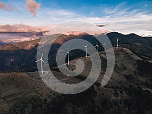 Wind turbines placed on top of mountains captured under a cloudy sky