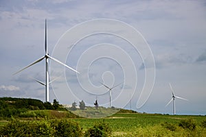 Wind turbines reflecting sun on a cloudy day in green rolling fields