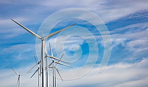 Wind turbines, renewable energy on  blue cloudy sky background. Wind farm