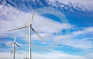 Wind turbines, renewable energy on  blue cloudy sky background. Wind farm