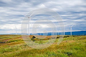 Wind turbines on a ridge of grassland and under gray sky