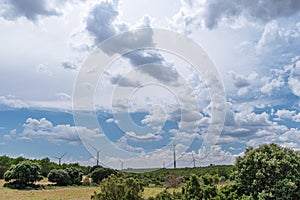 Wind turbines in rural landscape and stunning cloudy sky at the background. Environmentally friendly production of electrical