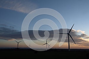 Wind turbines, silhouetted against the sunset. In the English countryside, Devon, UK