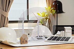Wind turbines and solar cells. House on the table. Renewable energy concept. Portable solar panel and wind turbine model