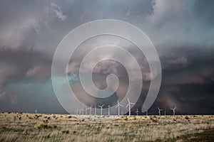 Wind turbines spin in strong winds as a dark storm approaches