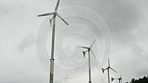 Wind turbines are spinning on cloudy sky background in rainy season. Green energy generation.