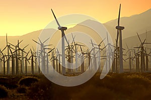 Wind turbines at sunset generating power as a fire is out of control burning nearby Palm Springs, California.