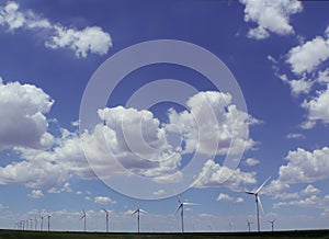 Wind turbines under beautiful cloudy sky stretching out over flat land in rows - alternative energy - Copy space