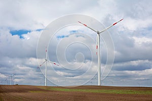 Wind turbines in wind farm against cloudy sky