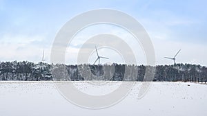 Wind Turbines in a winter field near a forest in Germany