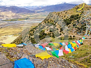 Wind wavering Buddhist Tibetan Chinese prayer flags with Sanskrit calligraphy written decorating mountain valley in Tibet, China