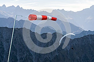 Windbag and Paraglider flying above Mountain Silhouette. Bad wind conditions. Allgaeu, Oberstdorf, Alps, Germany photo