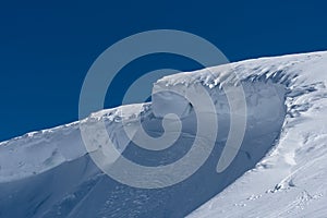 Windblown curved snow ridge in winter sunshine