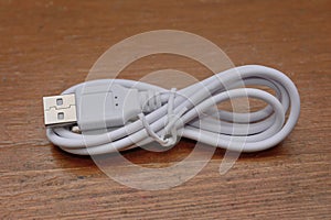 The winded cable for charging and synchronization of the smartphone on a wooden background