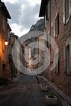 winding alley of Villefranche de Conflent at dusk. There is a street lamp with warm light
