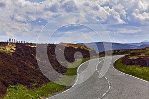 Winding asphalt road Through The countryside under cloudy sky