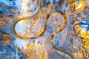 Winding asphalt road in sunny winter morning from above