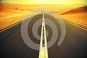 Winding black asphalt road through the sand dunes of Liwa oasis, United Arab Emirates