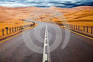 Winding black asphalt road through the sand dunes of Liwa oasis, United Arab Emirates