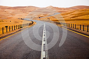 Winding black asphalt road through the sand dunes of Liwa oasis, United Arab Emirates