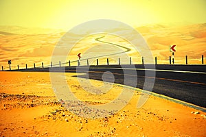 Winding black asphalt road through the sand dunes of Liwa oasis, United Arab Emirates