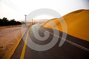 Winding black asphalt road through the sand dunes of Liwa oasis, United Arab Emirates