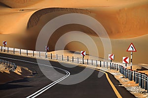 Winding black asphalt road through the sand dunes of Liwa oasis, United Arab Emirates