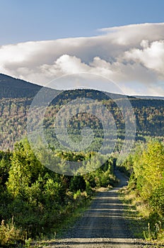 Winding dirt road hills clouds morning