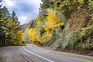 Winding highway road in autumn forest with yellow trees on the hills