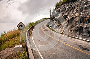 Winding mountain asphalt road with road sign to the sky.