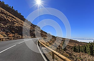 Winding mountain road against the sun in daytime, one of the most dangerous roads in Tenerife, Spain