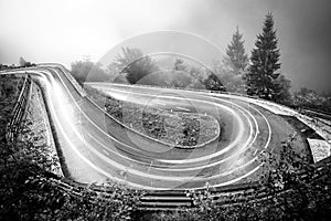 Winding mountain road with car lights. Foggy wet weather and low visibility. Alps, Slovenia.