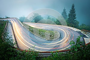 Winding mountain road with car lights. Foggy wet weather and low visibility. Alps, Slovenia.