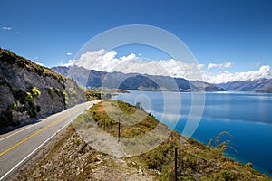 Winding mountain road lies in the foreground of a breathtaking landscape in Queenstown, New Zealand
