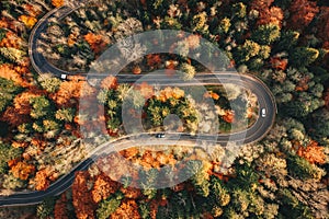 Winding mountain road trough the forest in the autumn with cars