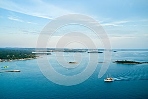 The winding picturesque coast of Croatia with small islands near the coastline. A tourist boat is sailing on the sea.
