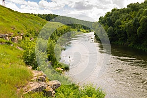 Winding river on a riffle in a summer forest in cloudy weather with rain clouds. Landscape in the river forest