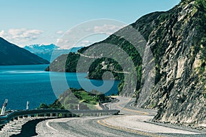 Winding road along mountain cliff and lake