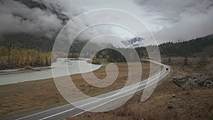 Winding road along river on a cloudy autumn rainy day, Siberia, Altai