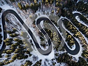 Winding road from high mountain pass, in winter time. Aerial view by drone