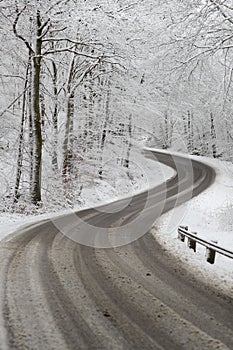 a winding road in the middle of a winter forest is covered in snow