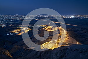 Winding road in mountains against illuminated city