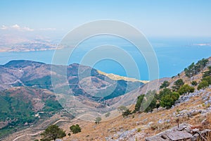 Winding road on mountainside at the coast with blue sky and ocean far below.Aerial view to sea from mountains. Travel