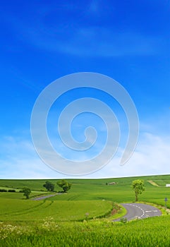 A winding road road in the field and blue sky