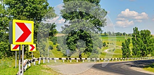 Winding road with steep turns in the hilly terrain. Green field