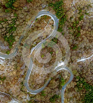 Winding road in the transition from autumn to winter, snow at a germany roa, filmed straight from above.
