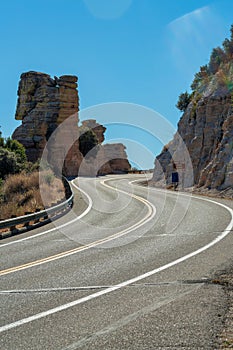 Winding road for transportation of cars and vehicles with yellow and orange lines and metal gaurd rail with blue sky photo