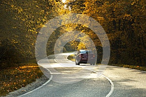 winding rual road with car inside colorful autumn forest