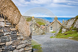Winding street with several restored thatched cottages in Garenin or Gearrannan Blackhouse Village photo