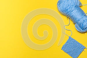 Winding of threads, spokes and knitted product from blue threads on a yellow background. Knitting.
